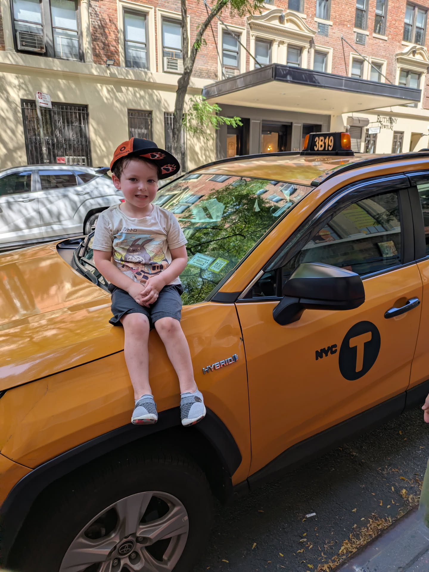 My son sitting on the hood of a taxi in New York City